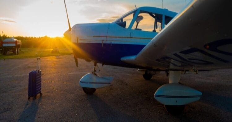 A small airplane on a runway with the sunset behind it.