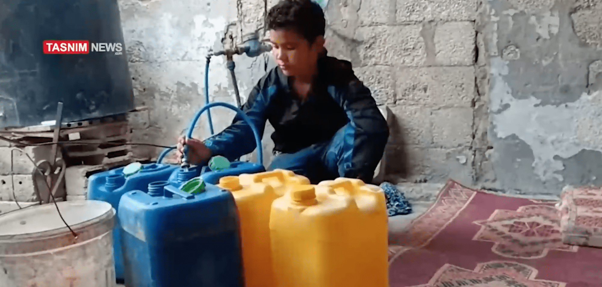 A Palestinian chilld fills containers with water from a hose early in the war.