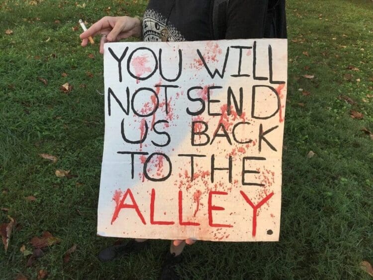 An abortion protest sign referencing women performing their own abortions when it wasn’t legal in the past.