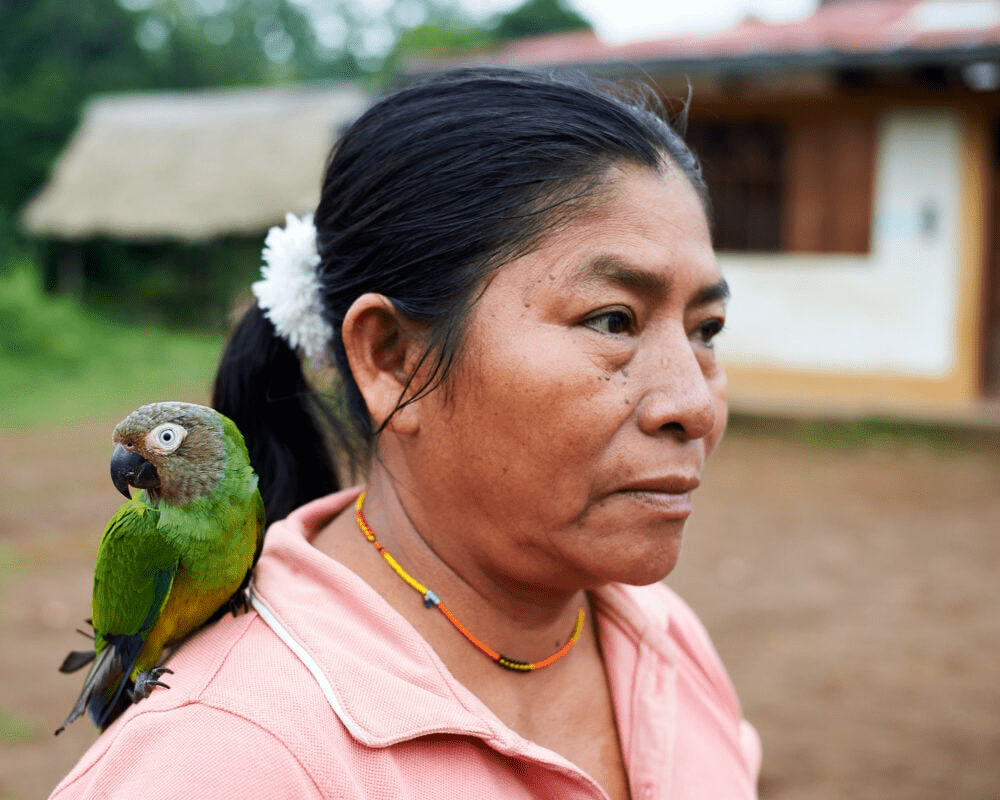 Planting trees to save the Peruvian rainforest. A woman with a parrot on her shoulder