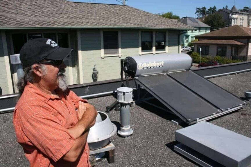 Ditch The Grid: How To Transition To Solar Energy Like A Pro Hot water solar systems. A man on a roof next to his system