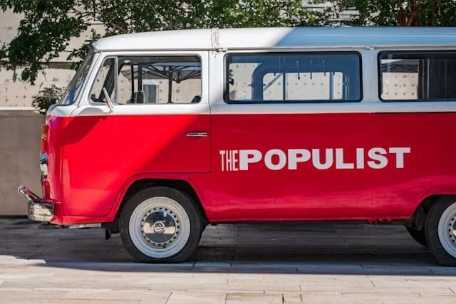 A red VW van with The Populist painted in white on its side.